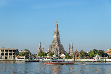 Beautiful temple of dawn Wat Arun Ratchawararam buddhist temple famous with boat and blue sky sunny day travelin Bangkok, Thailand.