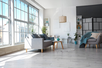 Interior of light living room with armchair, grey sofa and coffee table