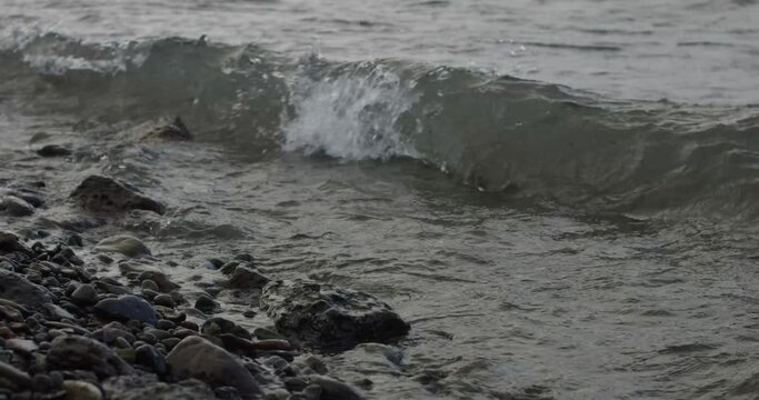 Close up waves crashing on a rocky shore in a freshwater lake 