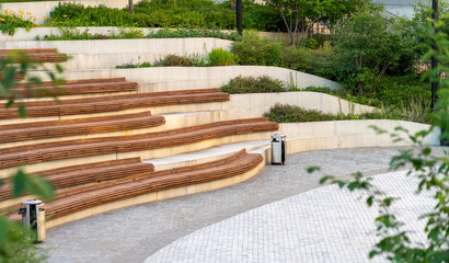 Curved concrete steps with wooden slats and flowers in the amphitheater in the city park
