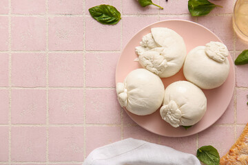 Plate of tasty Burrata cheese with basil on pink tile table