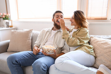 Happy couple in love eating popcorn at home