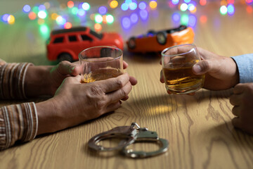 Two men clink whiskey glasses while in front of a bar in a restaurant. With a small car model on...