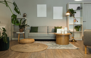 Interior of stylish living room with grey sofa and wooden coffee table at evening