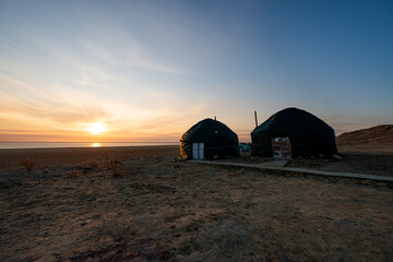 Yurt camp in the mid of desert against background of a beautiful sunrise in a blue sky.