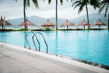 Luxury ocean view tropical resort swimming pool with stainless steel handrail, row of beach...