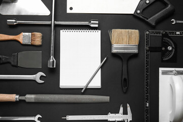 Set of construction tools, notebook and pen on black background