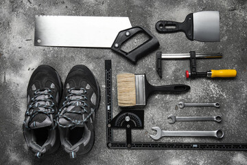 Set of construction tools and shoes on grey background