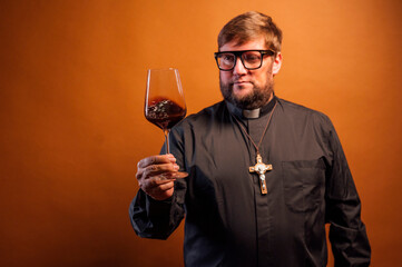 Portrait of a priest with crucifix and sunglasses drinking wine.