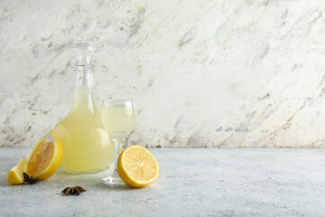 Bottle and glass of tasty Limoncello with citrus fruits on table
