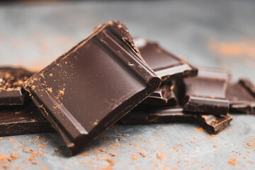 Heap of delicious dark chocolate pieces or cubes, chopped, broken chocolate bar on a dark background