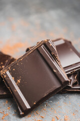 Heap of delicious dark chocolate pieces or cubes, chopped, broken chocolate bar on a dark background