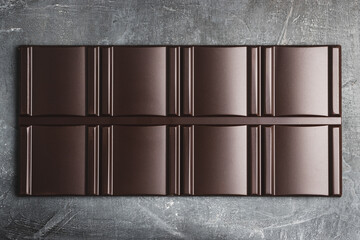 Delicious dark chocolate bar on a dark background, top view
