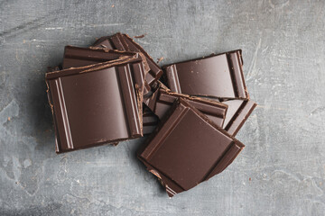 Heap of delicious dark chocolate pieces or cubes, chopped, broken chocolate bar on a dark...