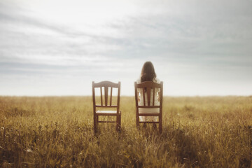 woman waits with pain sitting next to her lover's empty chair, abstract concept - 712350085