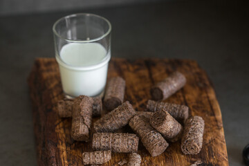 Waffle rolls and a glass of milk on an oak cutting board