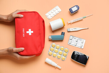 Female hands with first aid kit and pills on beige background