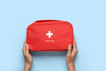 Female hands with first aid kit on blue background