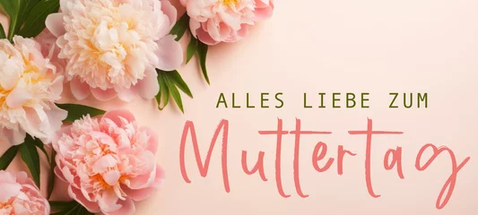 Fototapete Pfingstrosen Alles Liebe zum Muttertag Feiertag Grußkarte - Papier, Rahmen mit deutschem Text und Pfingstrosen auf pink aprikot Tisch Hintergrund, Draufsicht  © Corri Seizinger