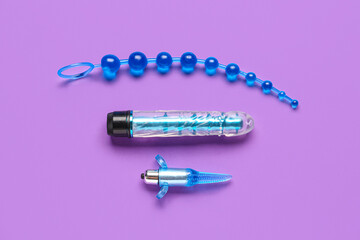 Different anal plugs and vibrator from sex shop on purple background
