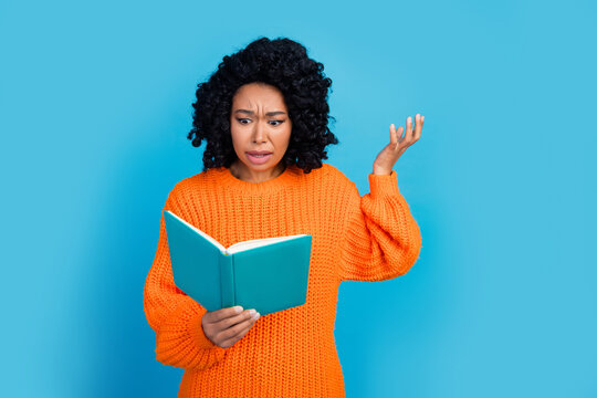Photo of attractive young woman read book confused irritated dressed stylish knitted orange clothes isolated on blue color background
