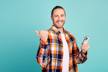 Portrait of optimistic guy wear flannel shirt hold smartphone indicating at discount empty space...