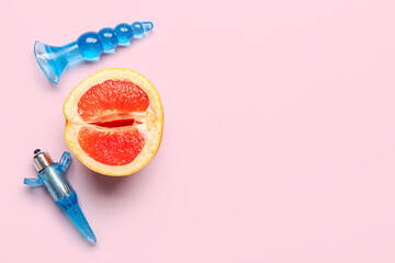 Anal plugs from sex shop and half of tasty grapefruit on pink background