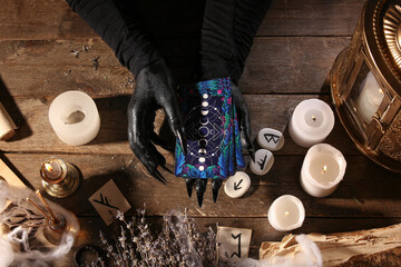 Witch with tarot cards on dark wooden table, top view