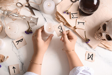 Witch with rune and burning candle on grunge table