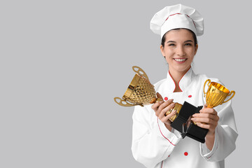 Female chef with gold cups on light background