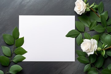 top view of white blank card near paper flowers with green leaves on grey background