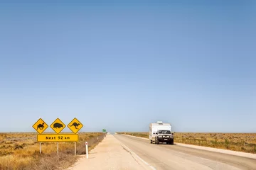 Foto auf Acrylglas Nullarbor Plain, South Australia - Car and caravan on the Eyre Highway, Nullarbor Plain, including iconic sign look out for camels, kangaroos, wombats. This is called the Treeless Plain. © Colin & Linda McKie
