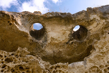 Top of the cliff in the form of a smiling face with eyes and a mouth. Texture, weathered limestone background. The bottom of the ancient sea. Abstract background.