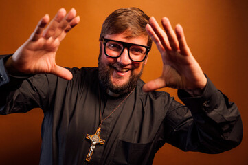 Portrait of a priest with crucifix showing the palm of his hands.