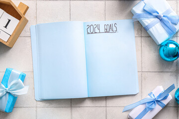 Notebook with text 2024 GOALS and Christmas decor on white tile background