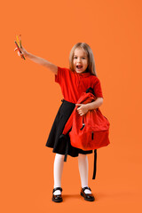 Cute little schoolgirl with backpack and pencils on orange background