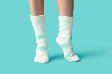 Legs of young woman in warm white dotted socks on blue background