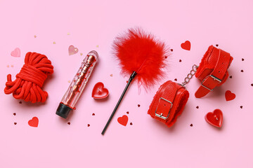 Red sex toys with candles and hearts on pink background