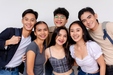 A diverse group of six happy young adults huddle together, smiling for a friendly group portrait...