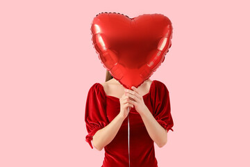 Beautiful woman with heart-shaped balloon on pink background. Valentine's Day celebration