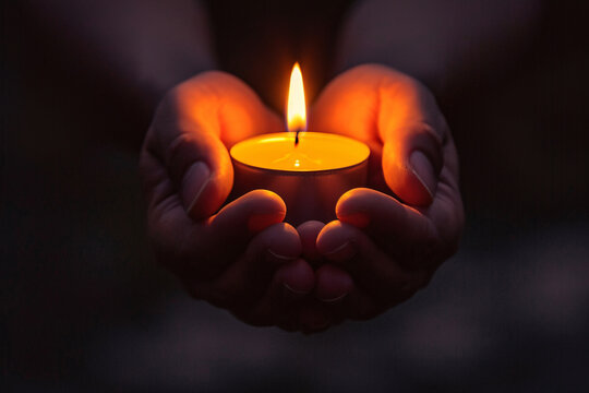 Hands holding a candle in the dark, depicting the concept of faith, hope, spirituality, or praying