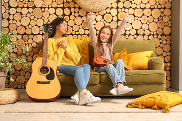 Young woman giving music lessons to teenage  girl with acoustic guitar at home