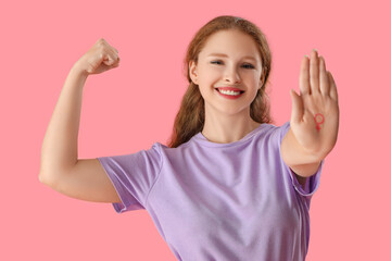 Young woman with drawn gender symbol showing muscles on pink background