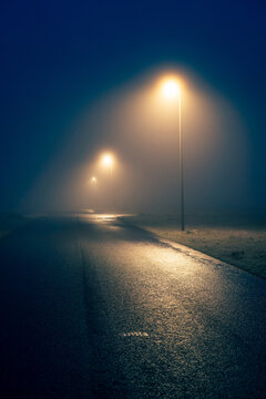 A rural road with streetlights in the fog.