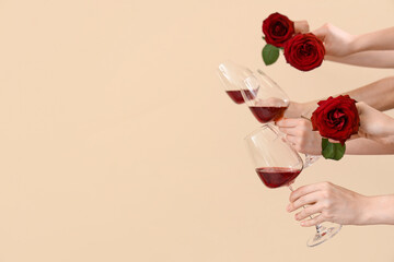 Women with glasses of red wine and roses on beige background. Valentine's Day celebration