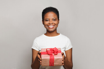 Cheerful happy young woman with gift present box standing on white background