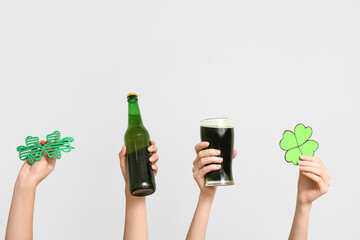 Hands with beer, clover and party glasses on light background. St. Patrick's Day celebration