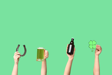 Hands with beer, horseshoe and clover on green background. St. Patrick's Day celebration