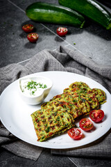 Zucchini waffles on a plate with sour cream and tomatoes