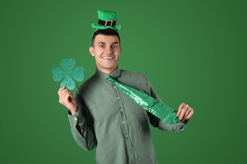 Happy young man with clover on green background. St. Patrick's Day